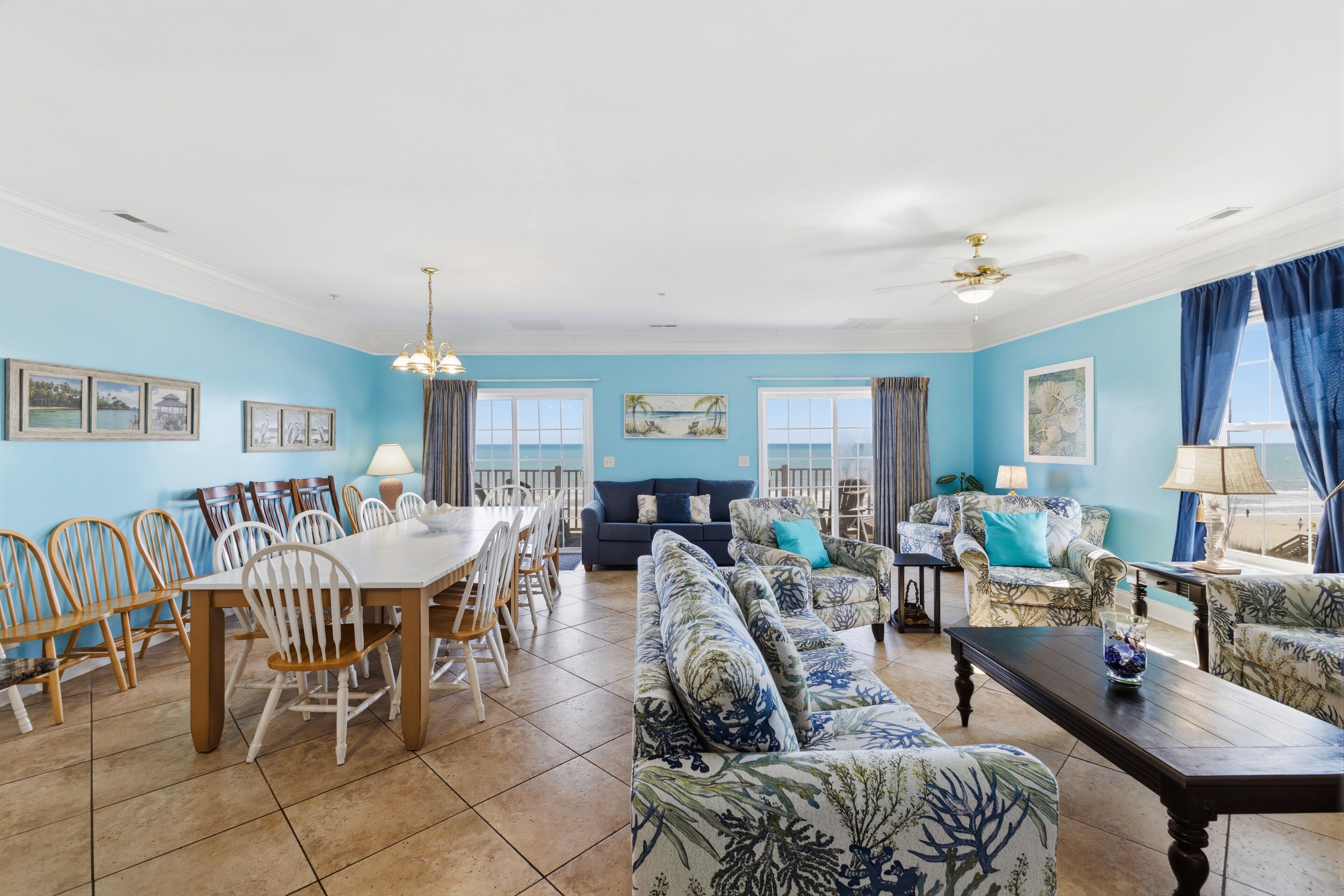 A spacious living room with a dining area, blue walls, and a ceiling fan.