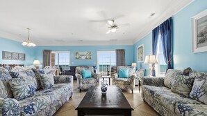A living room with patterned sofas, a central coffee table, and a ceiling fan.