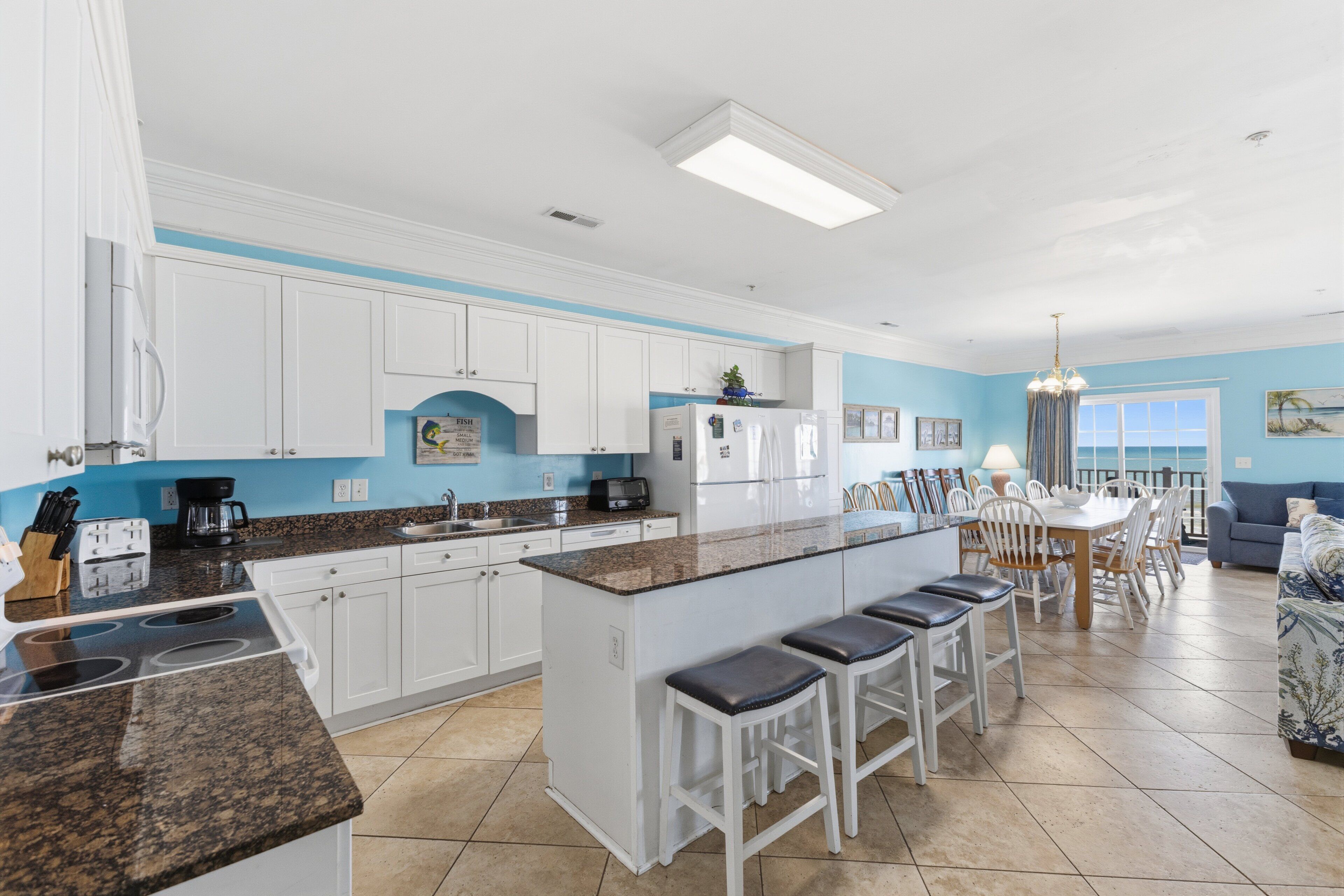 A modern kitchen with white cabinets, a granite countertop, and a central island with bar stools.