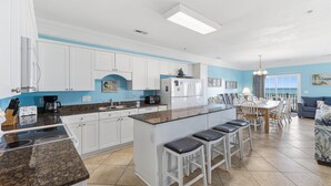 A modern kitchen with white cabinets, a granite countertop, and a central island with bar stools.