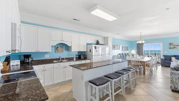 A modern kitchen with white cabinets, a granite countertop, and a central island with bar stools.