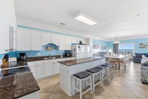 A modern kitchen with white cabinets, a granite countertop, and a central island with bar stools.