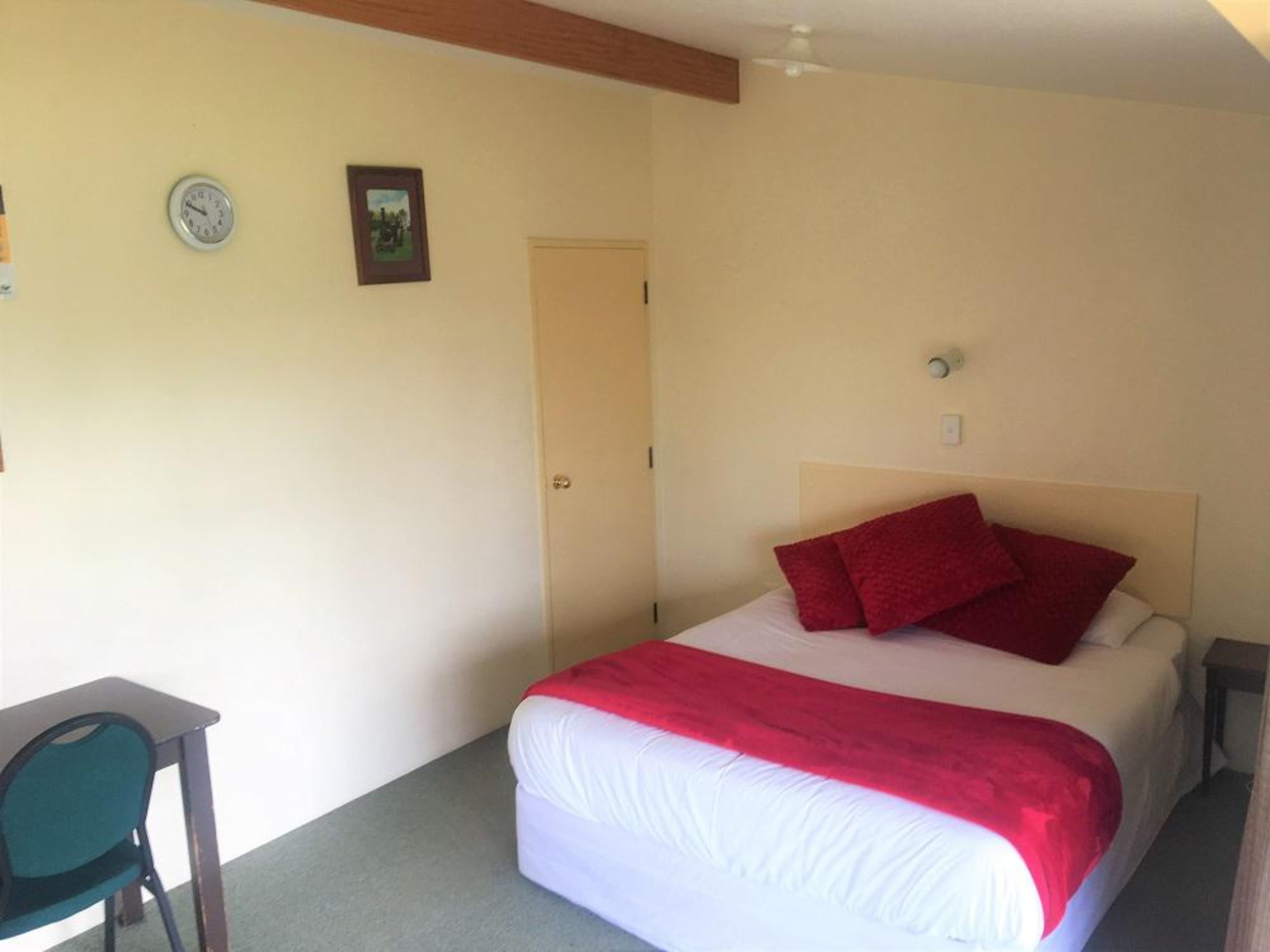 A bedroom with a bed, a desk, and a door.