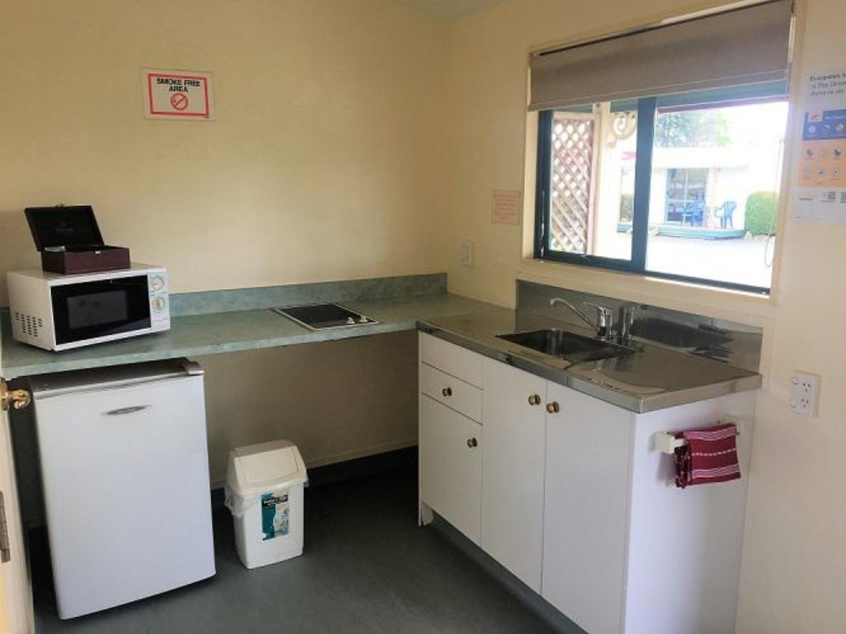 A compact kitchen with a microwave, refrigerator, sink, and a smoke-free sign.