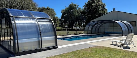 A swimming pool with a covered area and a greenhouse structure.