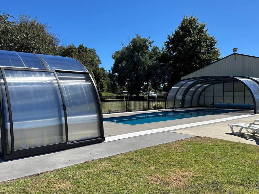 Una piscina con zona cubierta y estructura tipo invernadero.