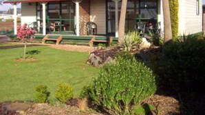 A single-story building with a green roof and a porch with benches. - Otorohanga Kiwi Holiday Park (Otorohanga)
