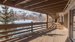 Eine Holzterrasse mit Blick auf eine verschneite Berglandschaft.