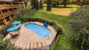 Ein Schwimmbecken mit überdachtem Bereich, umzäunt und mit einem Gebäude im Hintergrund, das einen Balkon hat.