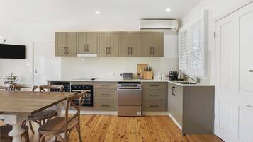 Una cocina moderna con suelo de madera, armarios empotrados, lavavajillas y un televisor de pantalla plana.