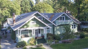 A green two-story house with a front porch, a chimney, and a well-maintained lawn. - Clean, comfortable, spacious Fort Grounds apartment: great location!  (Coeur d'Alene)