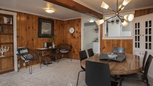 A dining area with a wooden table, black chairs, and a chandelier. There is a bookshelf with decorative items and a clock on the wall. - Clean, comfortable, spacious Fort Grounds apartment: great location!  (Coeur d'Alene)