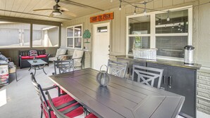 Un patio couvert comprenant une table à manger, des chaises et un ventilateur de plafond.