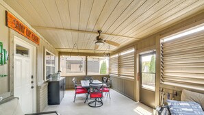 Un patio abrité avec une table et des chaises, un ventilateur de plafond et une enseigne indiquant « SHADY OAK CAFE ».