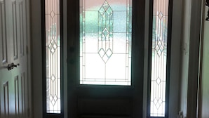 Una puerta con un diseño geométrico de vidrio, un marco de puerta oscuro y un suelo de baldosas.