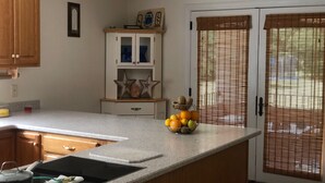 Una cocina con encimera de granito, estufa integrada, armarios de madera y un frutero sobre la encimera.