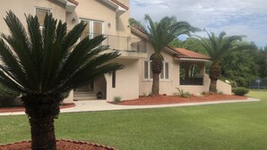 Una casa de dos pisos con balcón, un porche cubierto y un césped bien cuidado.