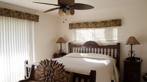 A bedroom with a wooden bed, a ceiling fan, two bedside tables with lamps, and a window with blinds. - Great Location Best Value Beautiful House and Guest House with Views (Sedona)