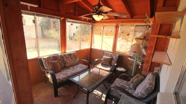 A sunroom with a ceiling fan, large windows, a sofa, a coffee table, and a lamp. - Great Location Best Value Beautiful House and Guest House with Views (Sedona)