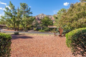 A residential area with a gravel driveway, a cactus sculpture, and a mountain in the background.