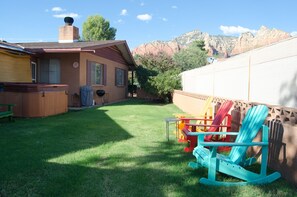 Un giardino sul retro con idromassaggio, barbecue e vivaci poltrone Adirondack.