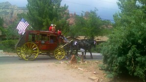 A red horse-drawn carriage with an American flag, a driver, and a passenger. - Great Location Best Value Beautiful House and Guest House with Views (Sedona)