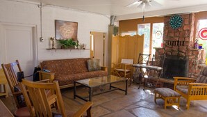A cozy living room with a stone fireplace, wooden furniture, and a dartboard. - Great Location Best Value Beautiful House and Guest House with Views (Sedona)