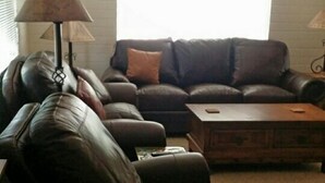 A living room with a dark leather sofa, a wooden coffee table, and a lamp. - Great Location Best Value Beautiful House and Guest House with Views (Sedona)
