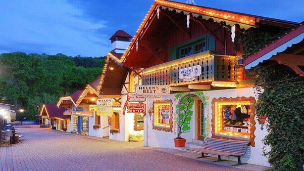 A traditional wooden building with multiple signs advertising local businesses, including ice cream and wooden toys. - 🌷 Das Tulip, the perfect place to stay in Helen. Center of town, Ground floor🏰 (Helen)