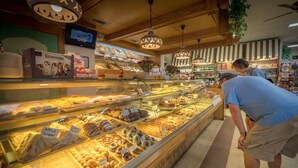 A bakery display case with various baked goods, a television screen, and wooden ceiling beams. - 🌷 Das Tulip, the perfect place to stay in Helen. Center of town, Ground floor🏰 (Helen)