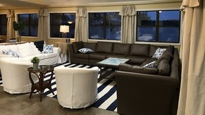 Un salon avec un canapé blanc et marron, une table basse en verre et un tapis à rayures.