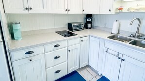 A kitchen with white cabinets, a toaster, a coffee maker, and a sink.