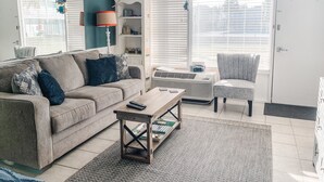 A living room with a sofa, armchair, coffee table, and a bookshelf.