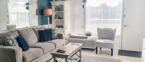 A living room with a sofa, armchair, coffee table, and a bookshelf.
