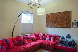 Una sala de estar acogedora con un sofá modular, una lámpara de pie, un cuadro abstracto de gran tamaño y una mesita baja con faroles decorativos.