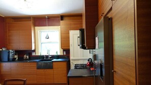 Une cuisine avec des meubles de rangement en bois, un réfrigérateur, un évier et une fenêtre.