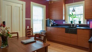Une cuisine avec des meubles en bois, un plan de travail noir et une fenêtre ornée de plantes.