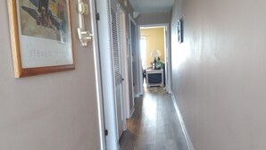 A hallway with wooden flooring, white trim, and a framed artwork on the left. - The Summit Resort,last min deal, Oct.1-3rd,10% disc. 20% off premisis drink,food (Panama City Beach)