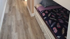A hallway with wooden flooring leading to a room with bunk beds, a door, and a light switch on the wall. - The Summit Resort,last min deal, Oct.1-3rd,10% disc. 20% off premisis drink,food (Panama City Beach)