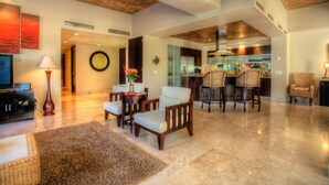 A spacious living area with a modern kitchen in the background, a dining area with wicker chairs, and a large rug on the floor. - Molino de Agua Next to Los Muertos Beach! 3BD Condo for rent in Los Muertos Beac (Puerto Vallarta)
