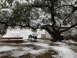 Zona al aire libre cubierta de nieve con bancos y una mesa, presumiblemente un parque o espacio público.