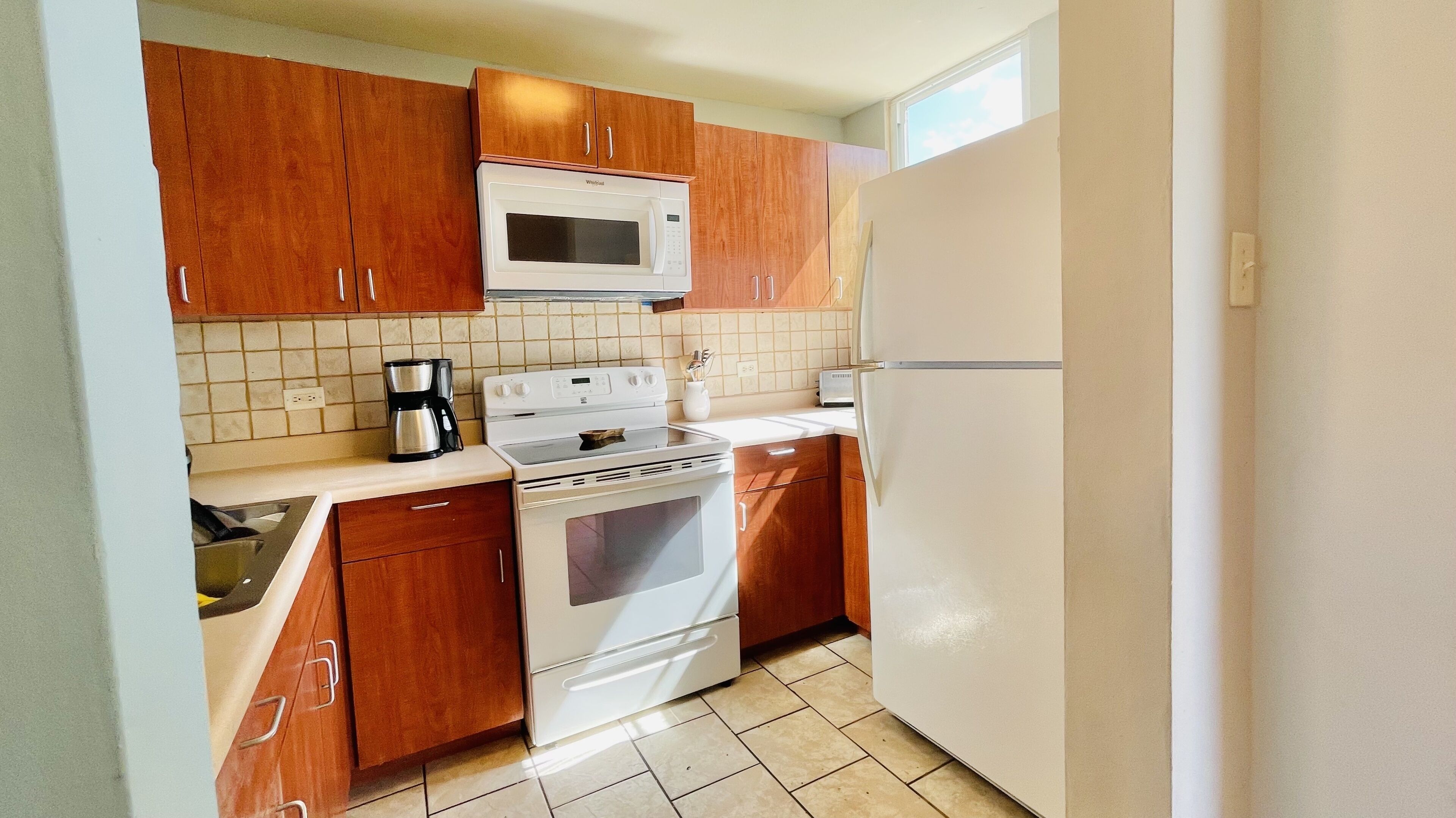 Una cocina compacta con armarios de madera, un microondas, una estufa y un refrigerador.
