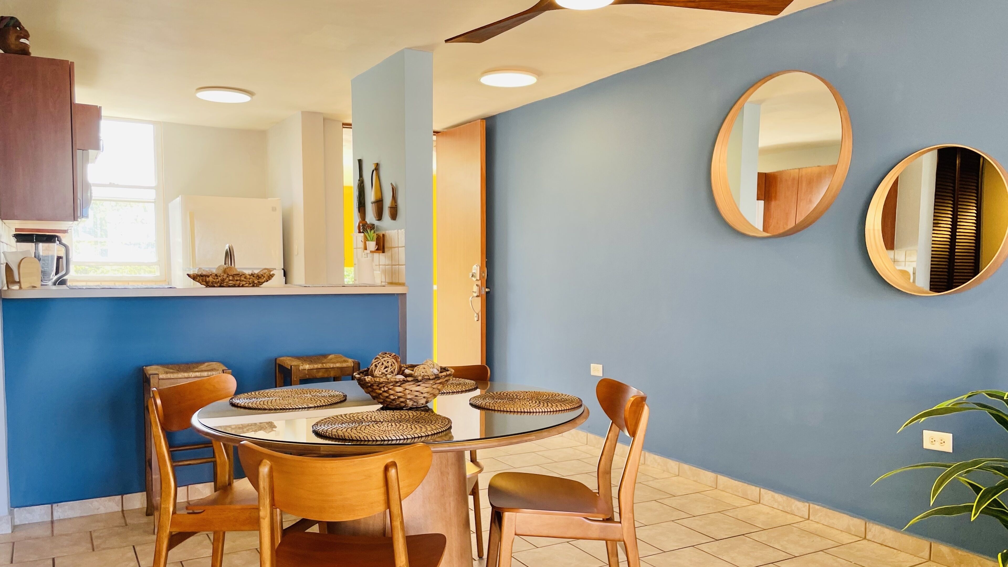 Zona pranzo con tavolo rotondo, quattro sedie e sottopiatti in tessuto.