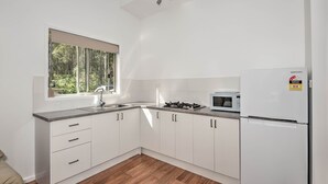 A modern kitchen with white cabinets, a stainless steel sink, a gas stove, a microwave, and a Samsung refrigerator.