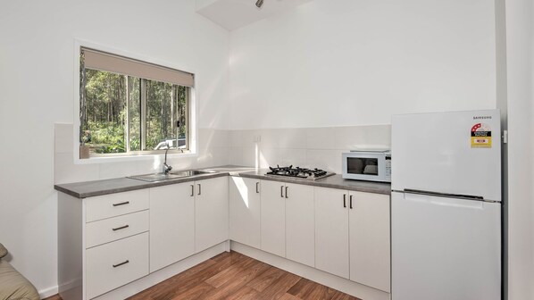 A modern kitchen with white cabinets, a stainless steel sink, a gas stove, a microwave, and a Samsung refrigerator.