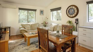 Una sala de estar con una mesa de comedor de madera, dos sofás, una mesa de centro y un reloj de pared grande.