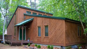 Een houten chalet met een groen dak, een veranda en een klein terras.