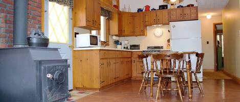 Una cocina con armarios de madera, una estufa y un comedor con sillas.