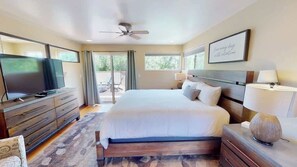 A hotel room with a large bed, a television, a ceiling fan, and a view of the outdoors. - Millcreek on Main Street - 4 Bed 2 Bath Private Ho (Moab)