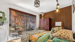 A bedroom with a bed, wooden paneling, a window with blinds, and a hanging light fixture. - TreeTops House near Bright with Mtn & pool views (Tawonga South)